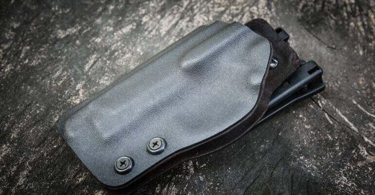 Handmade kydex holster for pistol on a grungy wood table